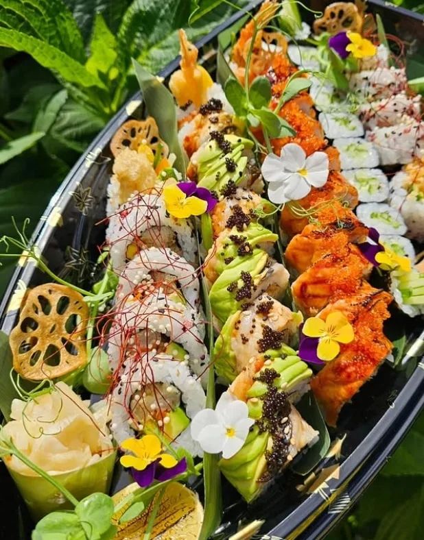 Couple Platter in the garden: prawn tempura rolls, avocado-topped rolls with black roe and torched salmon with tobiko, dressed with pansies and lotus crisps