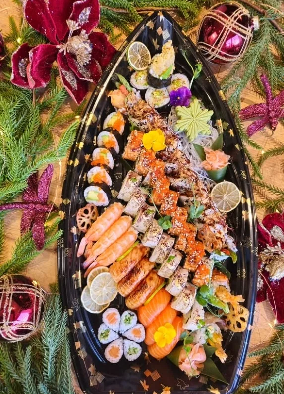 Party Platter from above: prawn nigiri, torched salmon rolls, roe-topped rolls, maki, wasabi and lime on a black boat platter